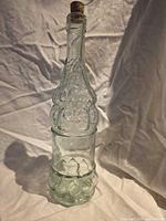 Full side view of embossed light green bottle with cork