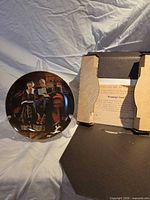 Plate on display stand next to open box showing certificate