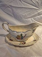 Gravy boat resting on underplate showing floral pattern and shape