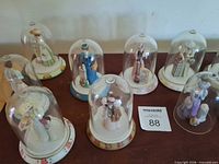 Group view of nine Avon lady figurines under glass domes on bases