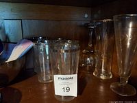 five silver-rimmed tumblers, two stemmed glasses visible