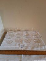 Eight etched champagne coupes arranged on cloth with ruler for scale