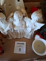 Three-angel porcelain figurine next to candle