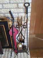 Overall group beside fireplace showing stand with brass tools, red bellows, black tongs