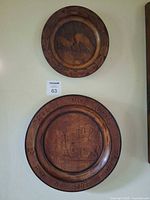 Both carved wood plaques on wall for scale and comparison