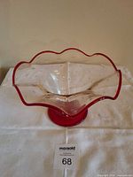 Front view of clear glass bowl showing red rim, pedestal base and bubble pattern