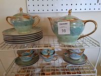 Full set on rack: teapot, sugar bowl, stack of plates, cups, saucers