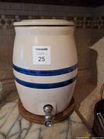 Front view of stoneware water dispenser showing blue bands and spigot