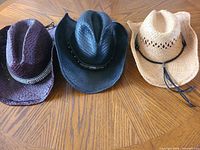 Front view of three woven straw cowboy hats