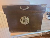 Front view of wooden ice box showing brass plaque and lid