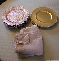 Stack of pink chargers, stack of gold chargers, folded pink napkins