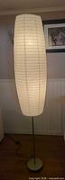 Full view of tall floor lamp with illuminated paper shade
