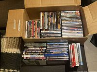 Open box showing large quantity of DVD movies and additional stack outside box