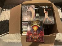 Open box showing top layer with Journey Live in Manila and Celine Dion DVDs plus other cases