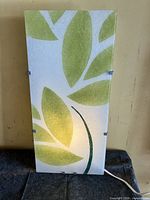 Front view of sconce illuminated showing leaf design