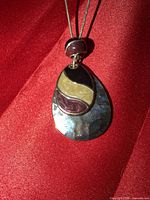 Close-up of teardrop enamel pendant and accent bead on silver-tone chain