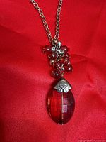 Close-up of pendant showing red faceted crystal, bead cluster, and silver-tone cap