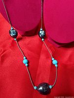 Full view of 32-inch blue bead necklace on display busts