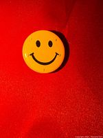 Front view of yellow smiley face lapel pin