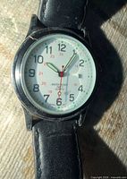 Close-up of watch dial showing white face, numerals, hands, Water Resist marking