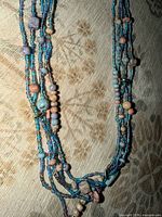 Full view of multi-strand blue seed bead necklace with mixed accent beads