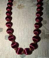 Close view showing burgundy silk-wrapped beads and gold-tone spacers