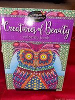 Front cover of Creatures of Beauty coloring book on stand