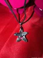 Close-up of clear crystal star pendant on black velvet cord