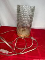 Full view of glass cylinder lamp on red surface