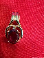 Front view of pendant highlighting stone and gold tone frame