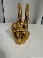Front view of goldtone hand statue forming peace sign
