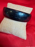 Front view of domed plastic bangle on burlap pillow