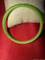 Full view of lime green plastic bangle on red fabric