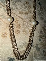 Close-up of one faux pearl and surrounding chain links