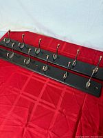 Two dark wooden coat racks with twelve hooks total laid side by side