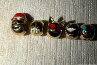 Front view of all five gold-tone emoji bead charms in a row