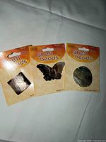 Front view of three packaged shell pendants: square, butterfly, oval