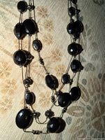 close view of necklace strands showing faceted black stones and chain detail