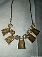 Close-up of necklace front showing five trapezoidal yellow/gold crystals and round clear crystals