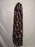 Full view of black scarf with dog and snowflake pattern on hanger