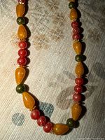 Close-up of bead arrangement: yellow-orange teardrops, red rounds, green spacers