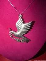 Front view of silver-tone dove ornament on display bust