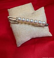 Brooch on display pillow showing front view with pearls