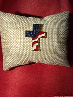 Front of enamel American flag cross lapel pin on cushion
