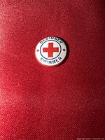 Front view of round Beginner Swimmer Red Cross pin
