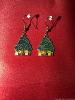Front view of both Christmas tree earrings on red background