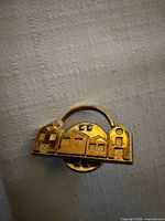 Front view of gold-tone village lapel pin