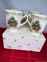 Four Mikasa Happy Holidays NY101 mugs on top of original box