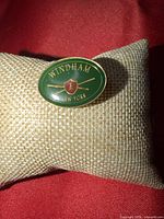 Front view of oval green enamel Windham New York pin on cushion