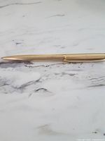 Full view of gold-tone mechanical pencil on marble surface